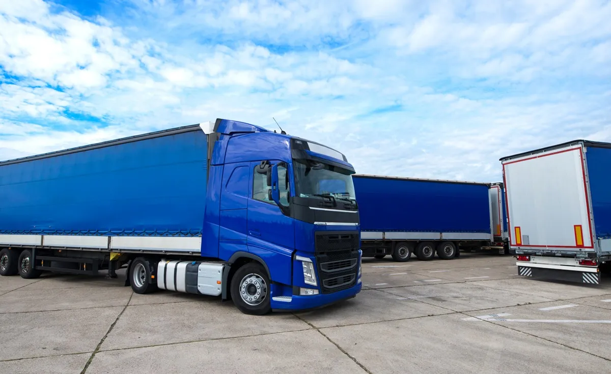 Blauer Lkw von OHAX mit Auflieger auf einem Betriebshof