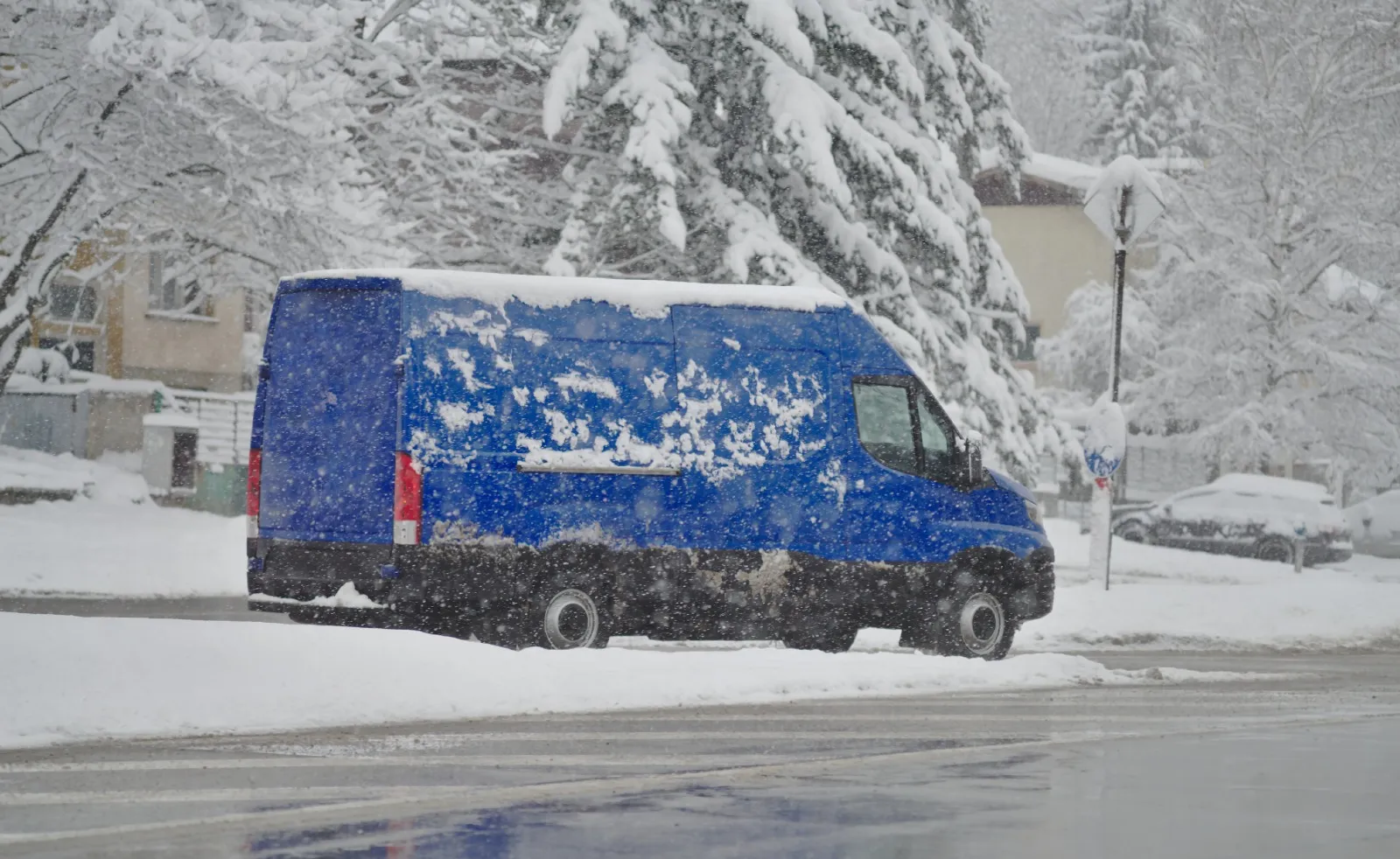 Blauer Transporter im verschneiten Wohngebiet